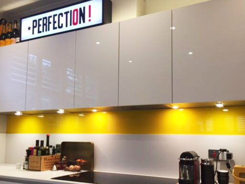 Dark yellow Made To Measure Glass Splashback in a kitchen with a perfection sign